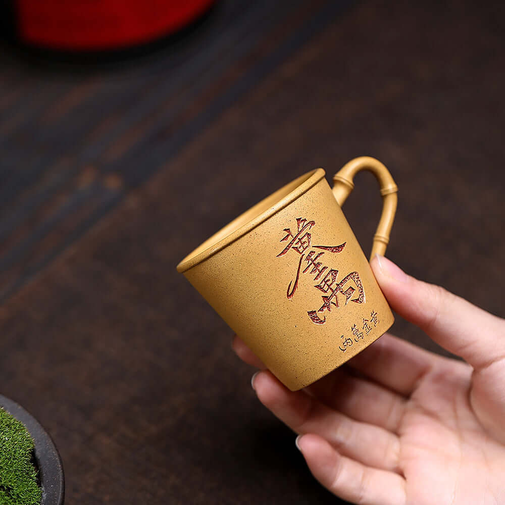 Handmade Yixing purple sand cup with bamboo handle, ideal for kung fu tea sets, showcasing original craftsmanship.