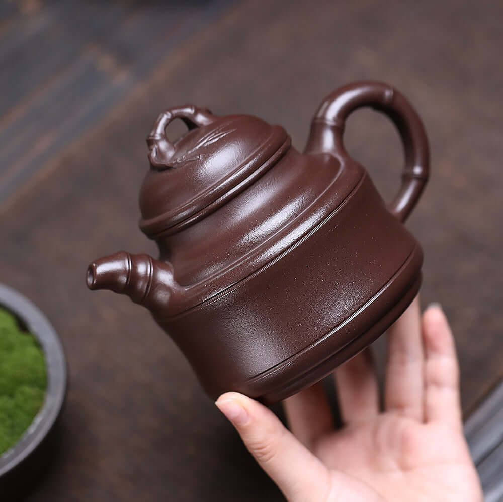 Handmade Yixing purple sand teapot held in hand, featuring original mineral deep well design, perfect for Kung Fu tea.