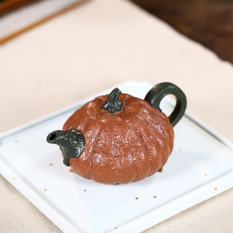 Handmade Yixing purple sand teapot shaped like a pumpkin, crafted with intricate details and a unique two-color design.