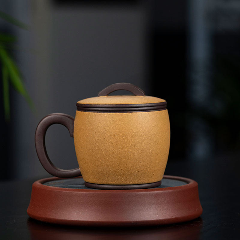 Handmade Yixing purple sand cup with lid on a brown saucer, showcasing original craftsmanship for tea lovers.