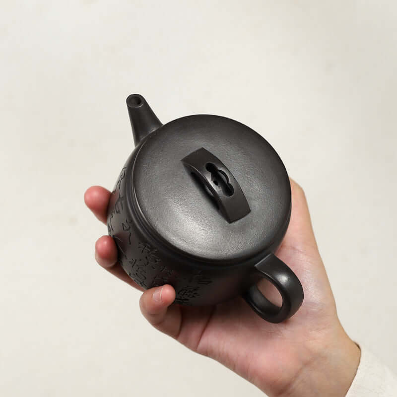 Handmade Yixing purple sand teapot held in hand, showcasing the intricate lid and craftsmanship.