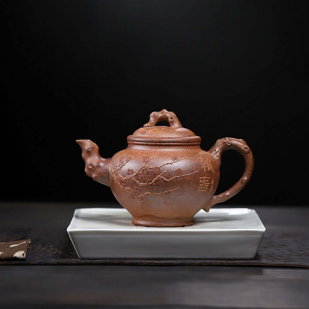 Handmade Yixing purple sand teapot on a white saucer, showcasing intricate designs and craftsmanship for kung fu tea.