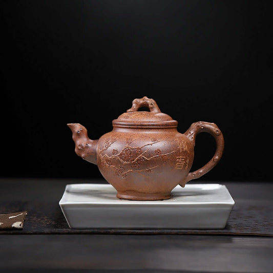 Handmade Yixing purple sand teapot on a white saucer, showcasing intricate designs and craftsmanship for kung fu tea.
