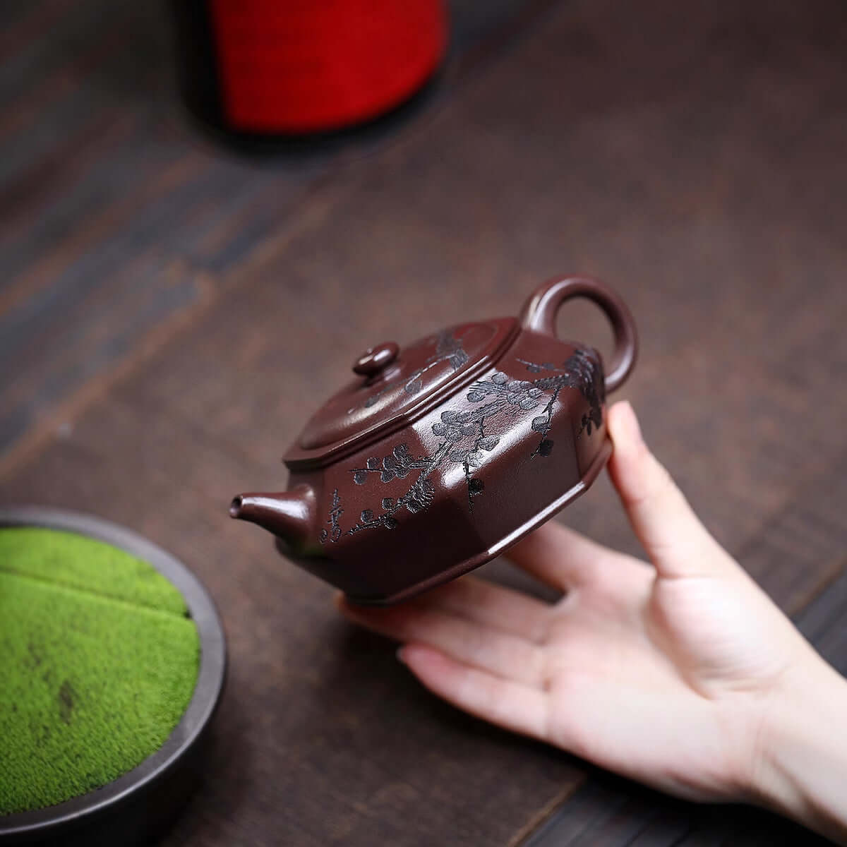 Handmade Yixing purple sand teapot featuring engraved plum blossoms, perfect for tea enthusiasts and collectors.