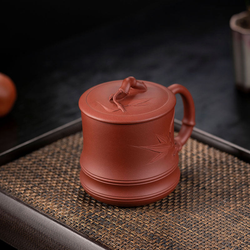 Handmade Yixing purple sand cup with bamboo cover, perfect for tea lovers and collectors.
