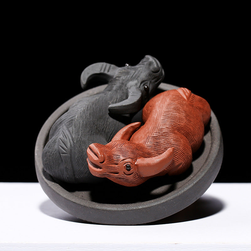 Handmade Yixing purple sand tea pet ornament depicting two playful buffalo figures in a circular base.