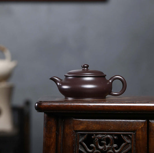 Handmade Yixing purple sand teapot on wooden table, ideal for Kung Fu tea, showcasing original craftsmanship and unique design.