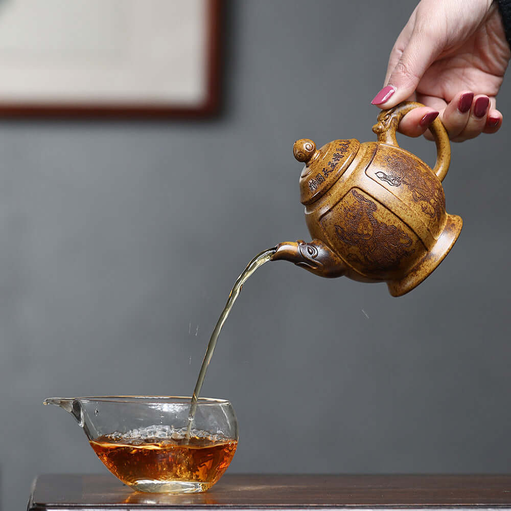 Handmade Yixing purple sand teapot pouring tea into a clear cup, showcasing traditional kung fu tea set craftsmanship.
