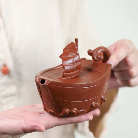 Handmade Yixing purple sand teapot in the shape of a boat, showcasing smooth craftsmanship and artistic design.