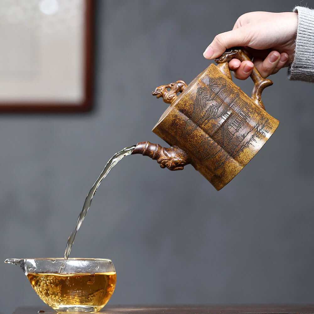 Handmade Yixing purple sand teapot pouring tea into a clear cup, showcasing artisan craftsmanship and elegance.