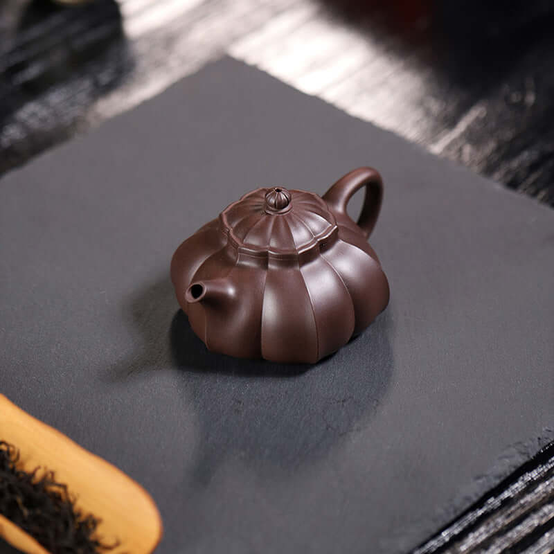 Handmade Yixing purple sand teapot with a unique half-moon design, perfect for brewing tea at home.