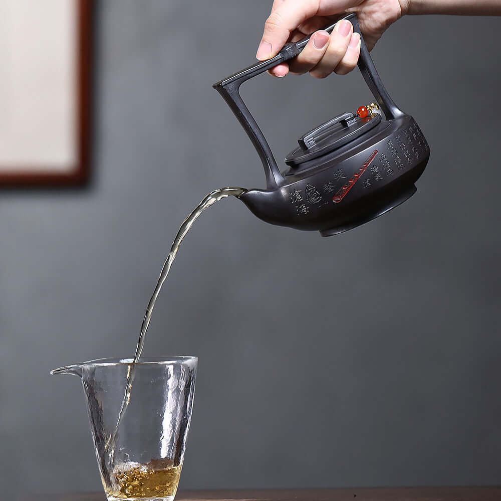 Handmade Yixing purple sand teapot pouring tea into a glass, showcasing original craftsman quality and elegance.