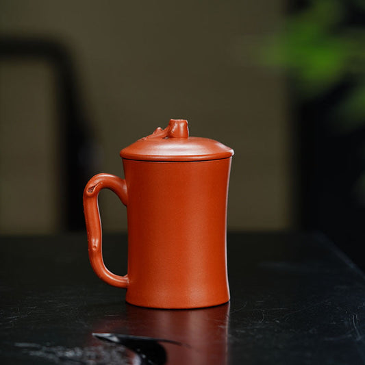 Handmade Yixing purple sand cup with lid, perfect for tea, showcasing craftsmanship and artful design.