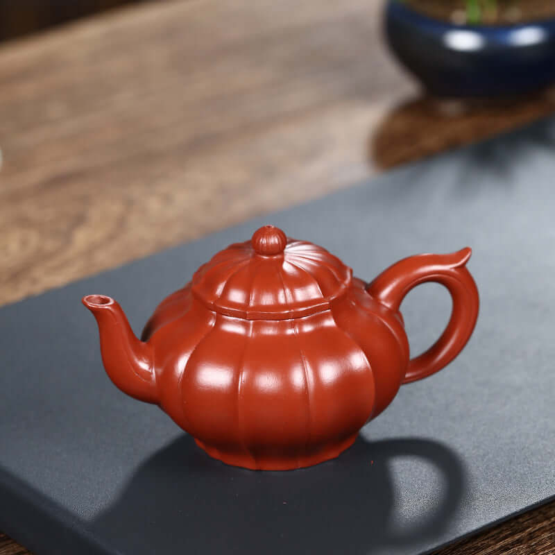 Handmade Yixing purple sand teapot with a pumpkin shape, showcasing traditional craftsmanship in rich earthy tones.