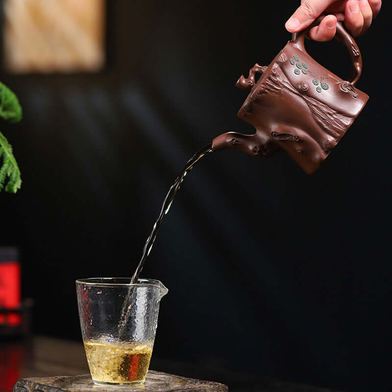 Handmade Yixing purple sand teapot pouring tea into a glass, showcasing original craftsmanship and design.