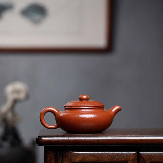 Handmade Yixing purple sand teapot on a wooden surface, showcasing traditional craftsmanship and design.