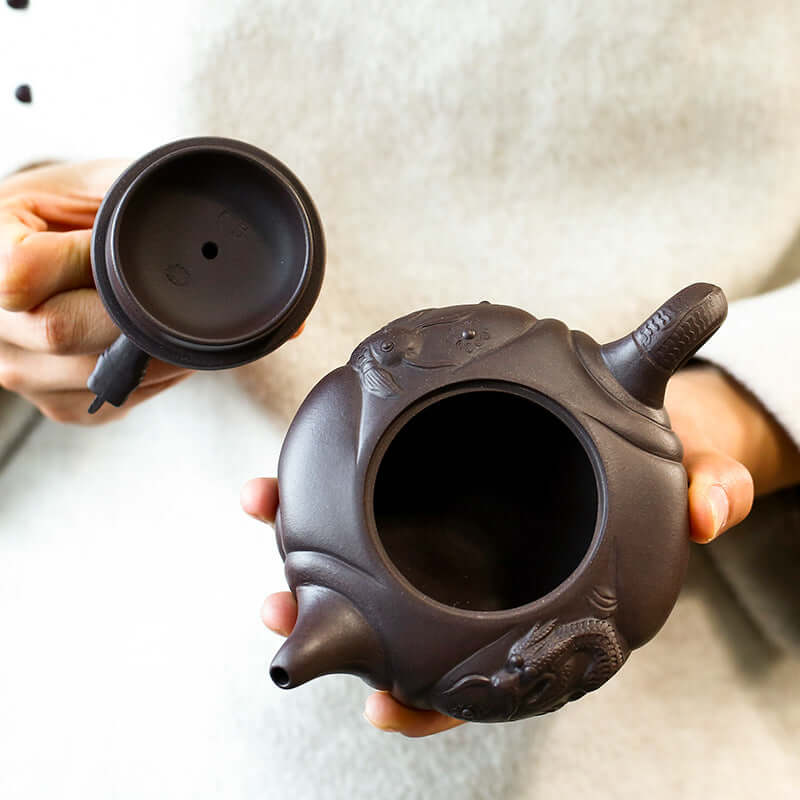 Handmade Yixing purple sand teapot featuring intricate fish design, showcasing craftsmanship and unique tea culture.