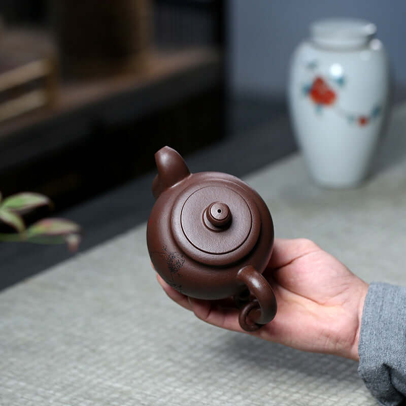 Handheld Yixing purple clay teapot showcasing its elegant design and unique craftsmanship.