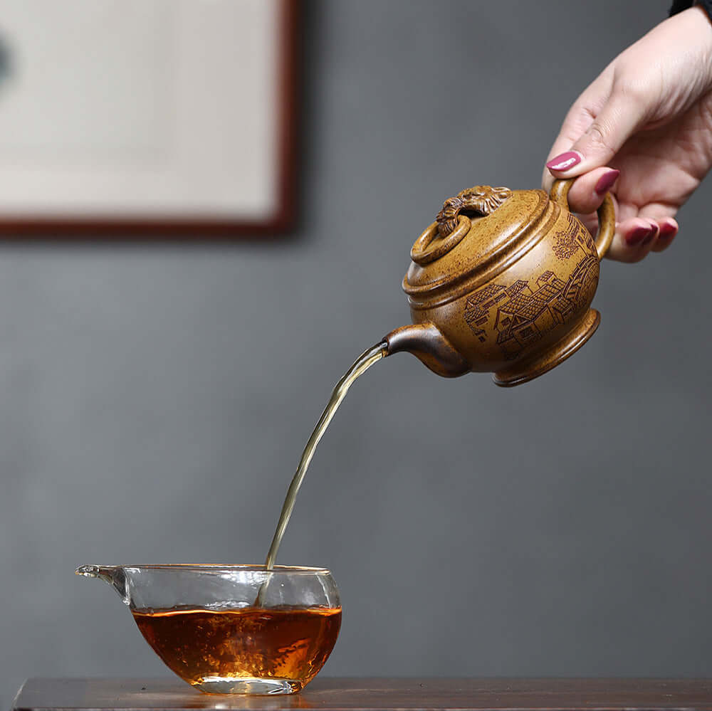 Handmade Yixing purple sand teapot pouring tea into a glass cup, showcasing traditional craftsmanship.