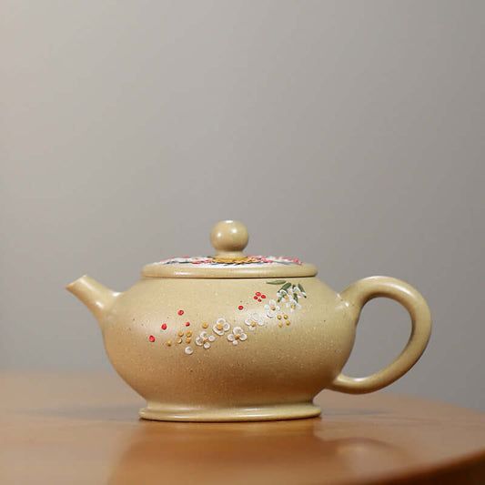 Handmade Yixing purple sand teapot with floral design and smooth beige finish on a wooden table.