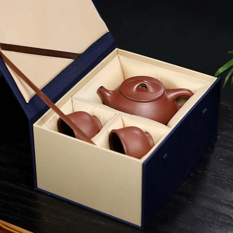 Handmade Yixing purple sand teapot set displayed in a gift box with two cups and a ladle.