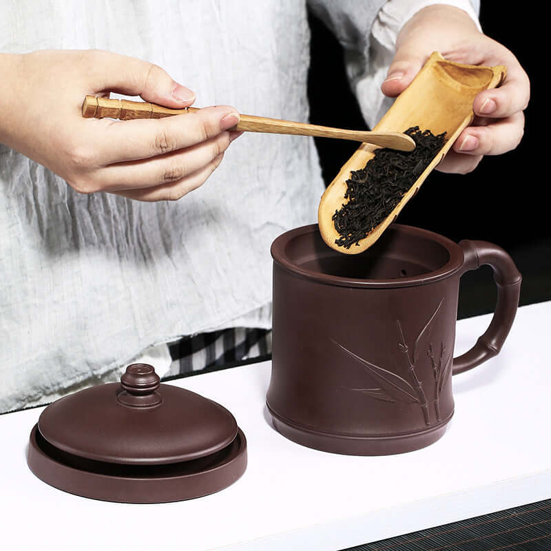 Handmade Yixing purple sand cup with a lid, designed for brewing tea, featuring bamboo leaf patterns.