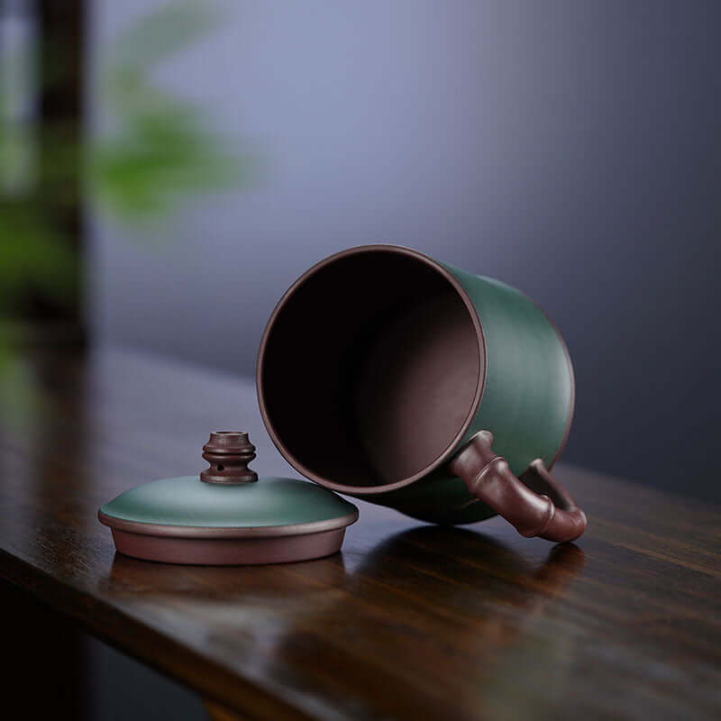 Handmade Yixing purple sand cup with a lid, showcasing artisan craftsmanship and elegant design for tea lovers.