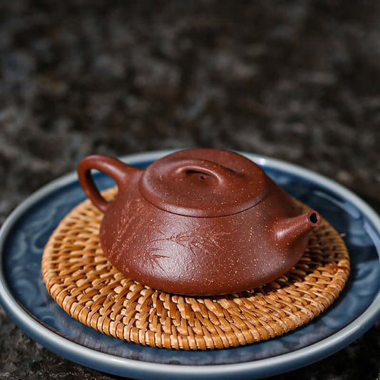 Handmade Yixing purple sand teapot on a woven coaster, showcasing fine craftsmanship and traditional design.