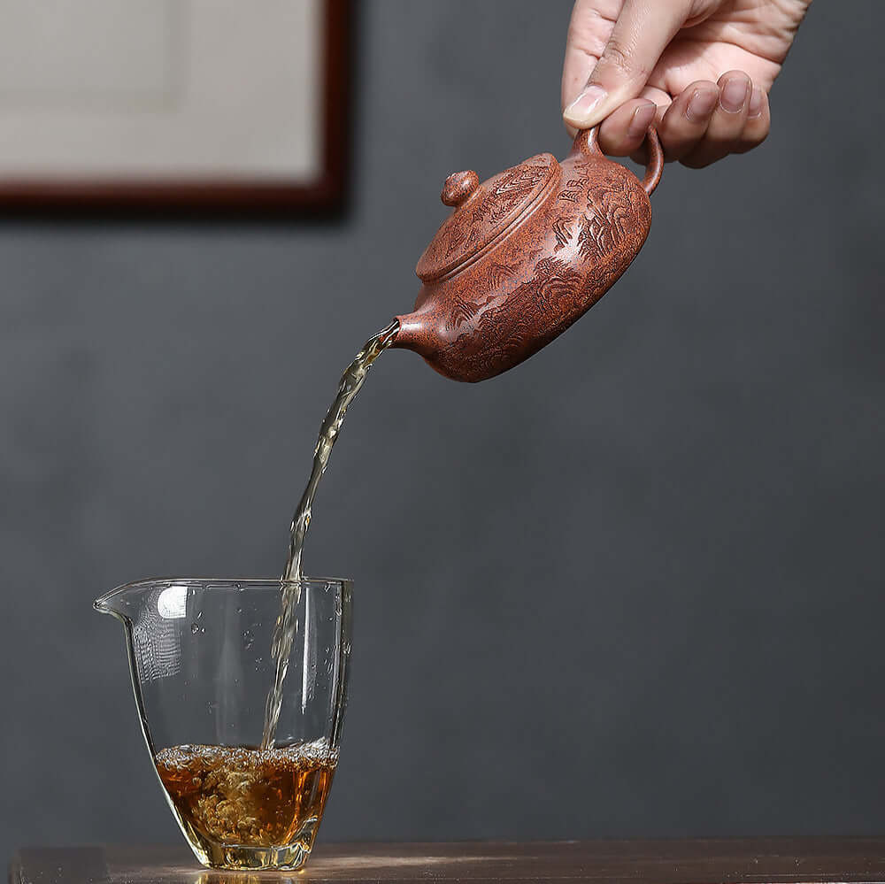 Handmade Yixing purple sand teapot pouring tea into a glass, showcasing traditional Kung Fu tea set craftsmanship.