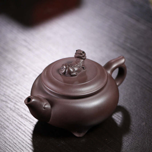 Handmade Yixing purple sand teapot with a detailed lid featuring a dragon motif, showcasing traditional craftsmanship.