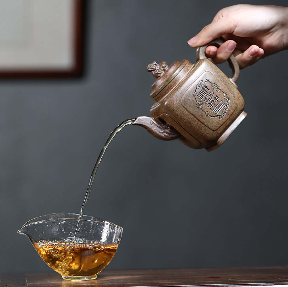 Handmade Yixing purple sand teapot pouring tea into a glass cup, showcasing original craftsmanship and traditional Kung Fu tea set.