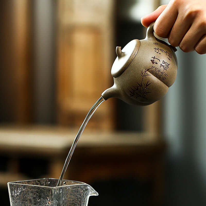 Handmade Yixing purple sand teapot pouring water, showcasing elegant craftsmanship and traditional design.