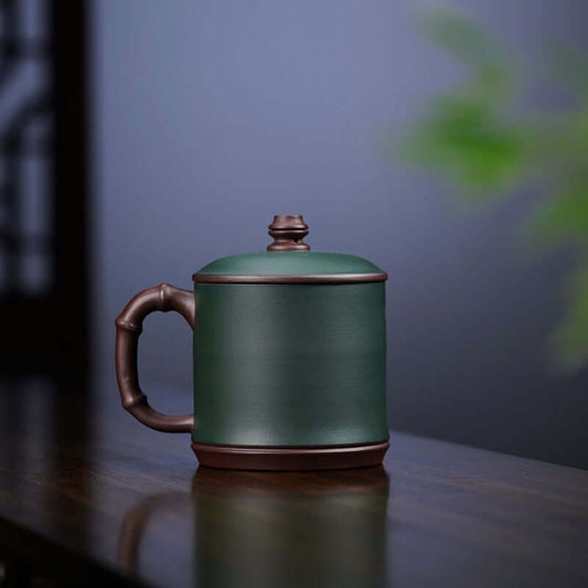 Handmade Yixing purple sand cup with bamboo handle, perfect for tea enthusiasts and collectors.