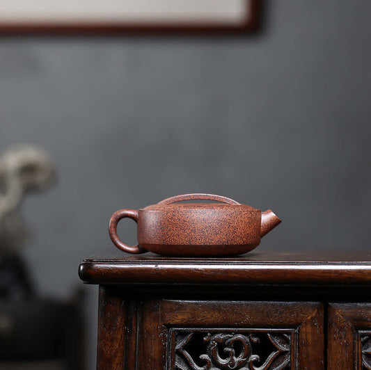 Handmade Yixing purple sand teapot on wooden table, showcasing original mineral star sand craft for tea brewing.