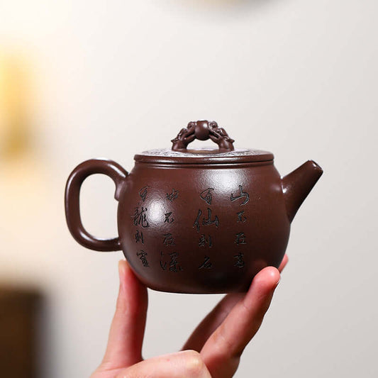 Handmade Yixing purple sand teapot with intricate design, held in hand, showcasing craftsmanship and elegance.
