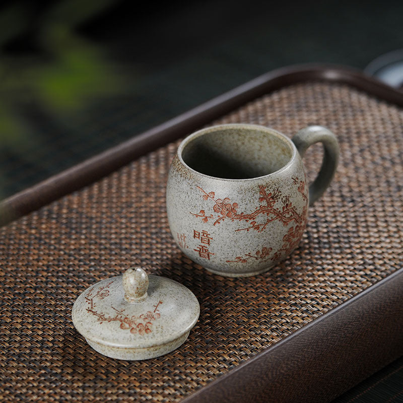 Handmade Yixing purple sand tea cup with lid featuring plum blossom design, showcasing traditional craftsmanship.