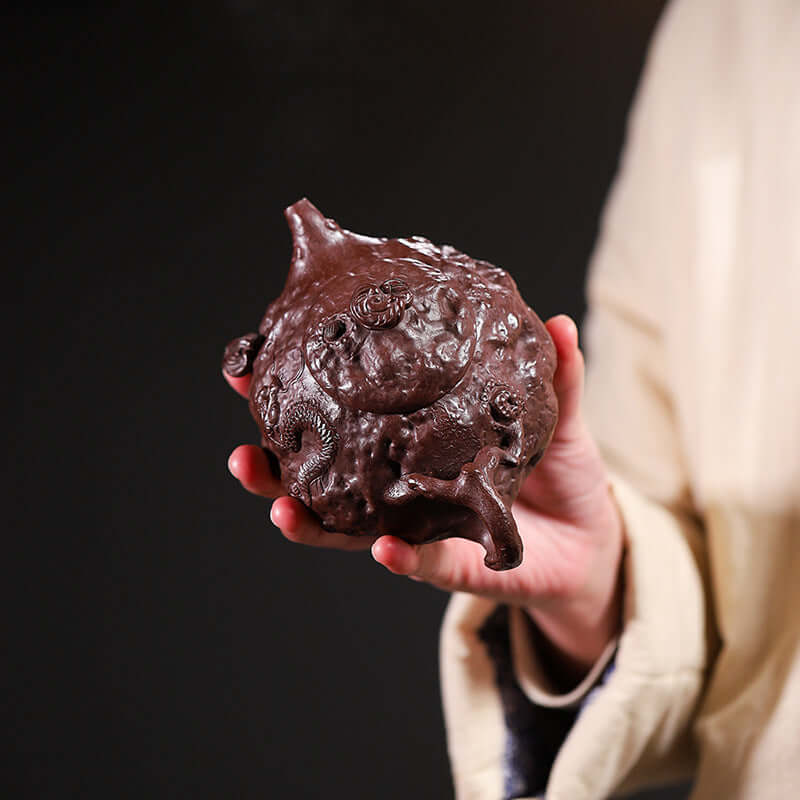 Handmade Yixing purple sand teapot held in hand, showcasing unique craftsmanship and original raw ore design.