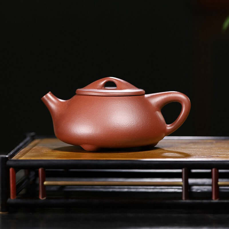 Handmade Yixing purple sand teapot on wooden tray, showcasing original craftsmanship and design.