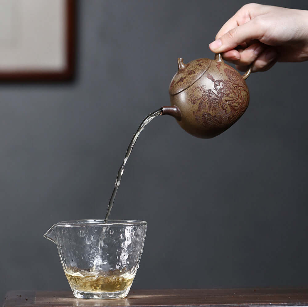Handmade Yixing purple sand teapot pouring tea into glass cup, showcasing original craftsmanship and unique design.