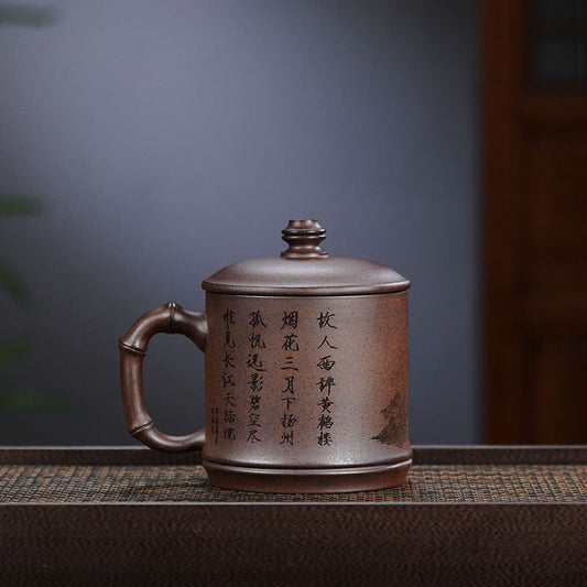 Handmade Yixing purple sand teacup with bamboo handle, featuring intricate carvings, perfect for tea lovers.