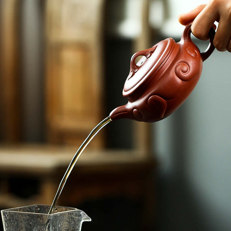 Handmade Yixing purple sand teapot pouring tea, showcasing elegant design and craftsmanship.