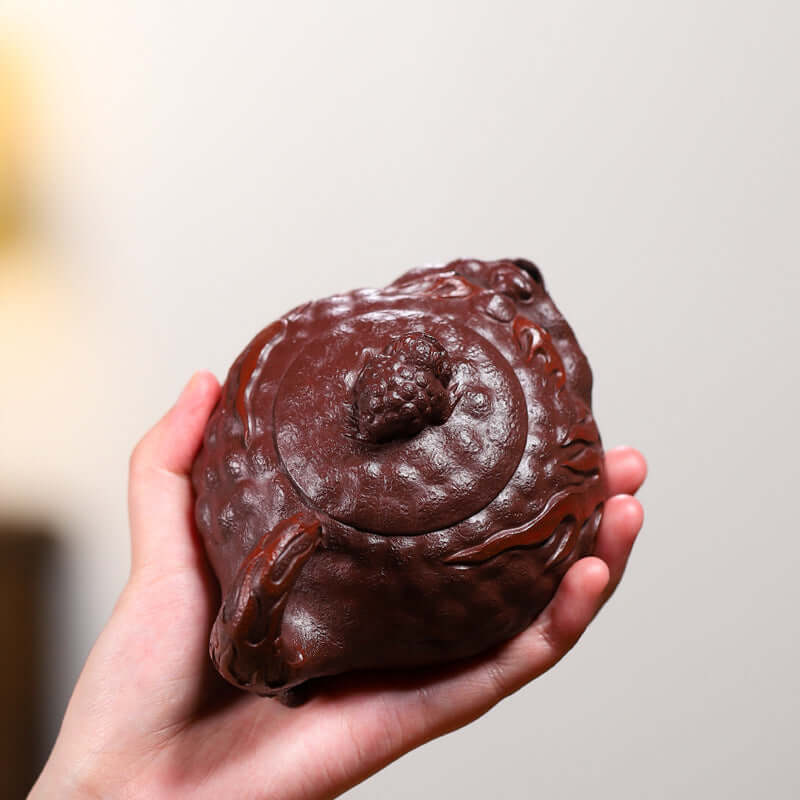 Handmade Yixing purple sand teapot shaped like a toad, showcasing intricate craftsmanship and rich color.