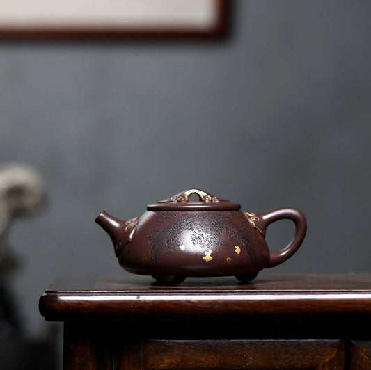 Handmade Yixing purple sand teapot featuring intricate gold detailing, showcasing traditional craftsmanship.