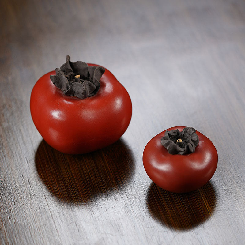 Handmade Yixing purple sand ornaments, featuring two red fruits with dark tops, ideal for tea table decor.