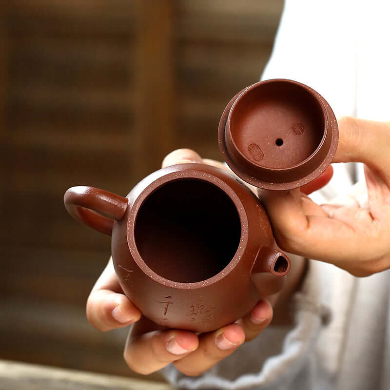 Handmade Yixing purple sand teapot shown from above, featuring an elegant round body and lid, highlighting its craftsmanship.