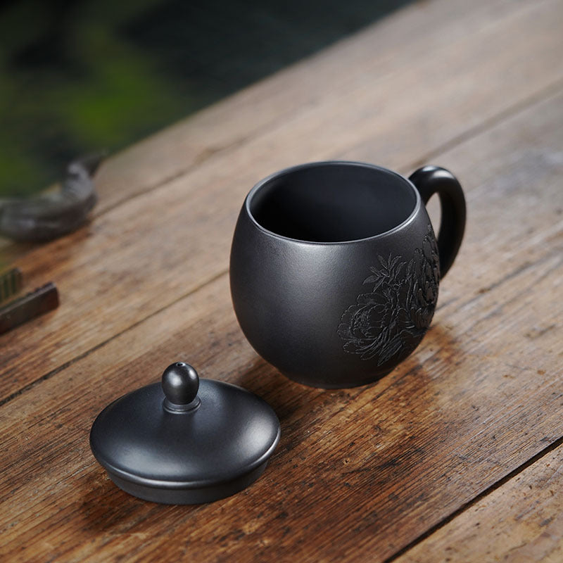 Handmade Yixing purple sand tea set with peony design, dark green enamel cover cup on wooden table.