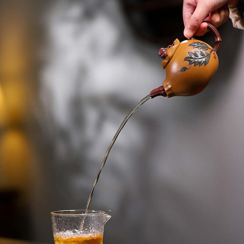 Handmade Yixing purple sand teapot pouring tea into a glass, showcasing its unique design and craftsmanship.