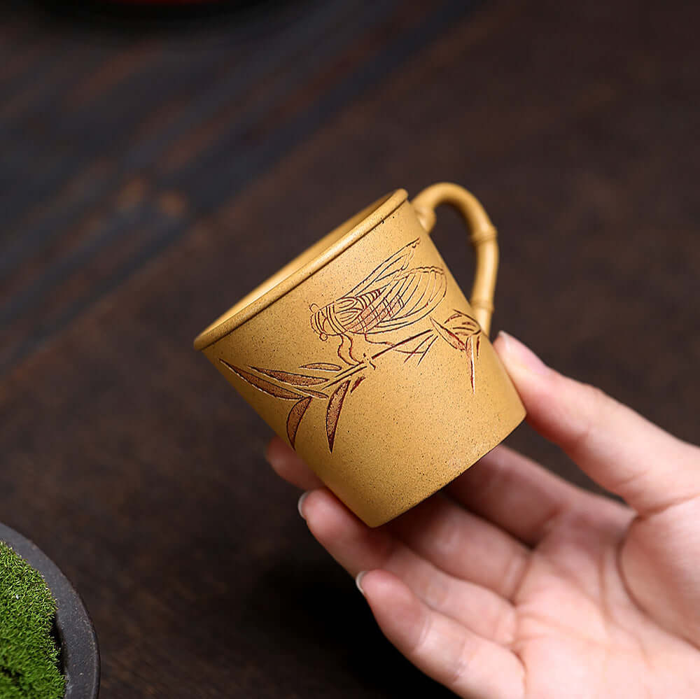 Handmade Yixing purple sand tea cup featuring bamboo carvings, perfect for kung fu tea set, showcasing master craftsmanship.