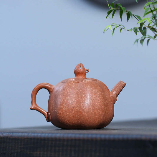 Handmade Yixing purple sand teapot shaped like a pomegranate, showcasing unique craftsmanship and natural clay texture.