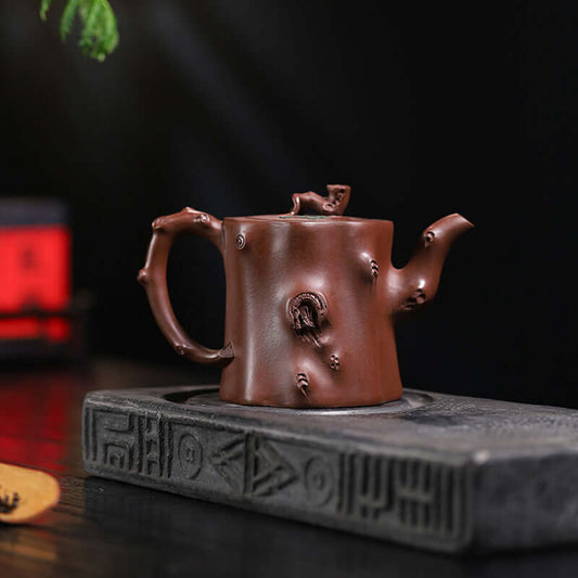 Handmade Yixing purple sand teapot on a dark stone tray, showcasing unique craftsmanship and rustic design.